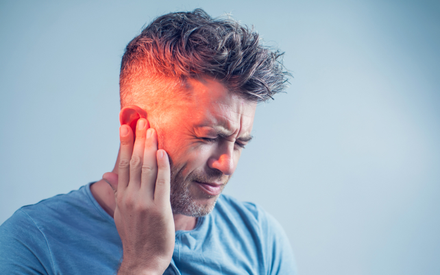 Man holding his hand over his ear in discomfort
