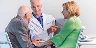 Audiologist discusses hearing loss with an elderly man.
