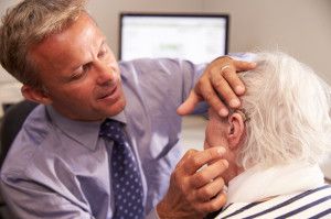 Audiologist adjusting a hearing aid on an elderly woman