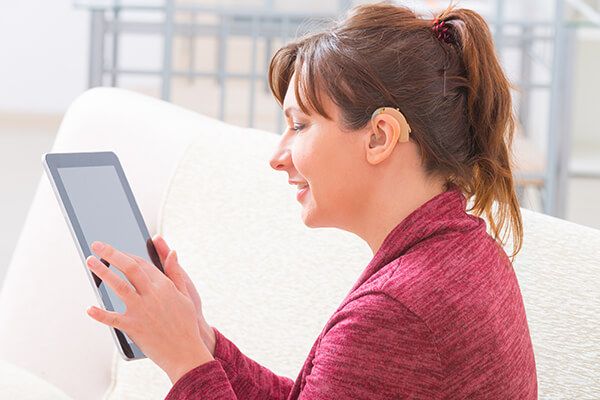 Woman with a behind the ear hearing aid using a tablet