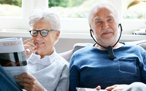 Elderly couple sitting together wearing hearing aids
