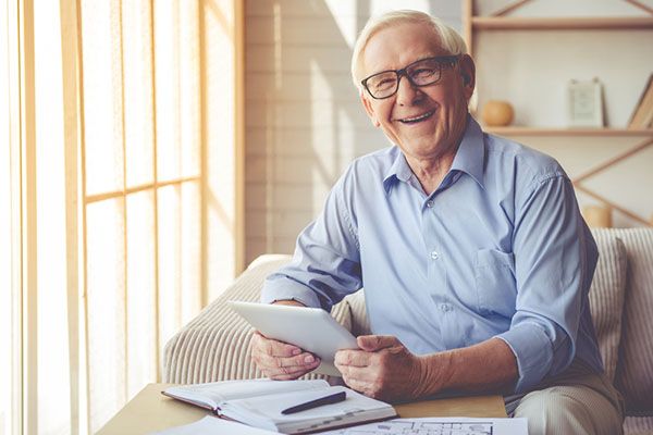 Elderly man with a notebook and tablet smiling