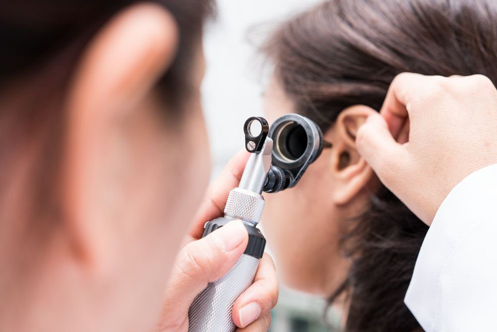 Audiologist looking into a woman's ear canal