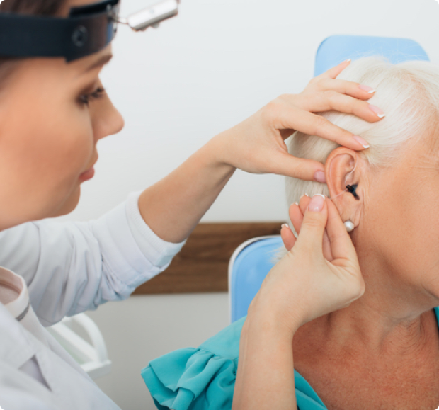 An audiologist inserting a hearing aid into a patients ear