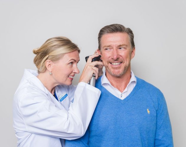 Audiologist looking in a middle aged man's ear canal